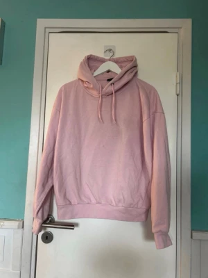 Ljusrosa oversized hoodie med huva - Mysig ljusrosa hoodie i oversized modell med stor huva och dragsnören. Tillverkad i mjukt bomullsmaterial och har ribbade muddar vid ärmslut och midja. Perfekt för en chill och avslappnad stil. Fläckar som inte fgår bort i tvätten men har inte testat behandla