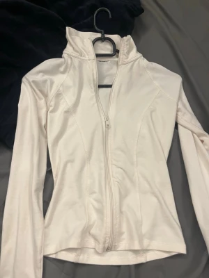 Vit zip up - Figurnära vit tröja med dragkedja, perfekt för gymmet eller en snygg vardagslook! Använd endast en gång, nästan som ny. Kostade runt 350 kr.
