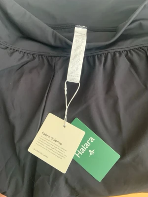 Svart sportig shorts med bred midja med inbyggda tights. - Snygg svart shorts med bred resår i midjan och inbyggda tights under kjoldelen. Tillverkad i ett lätt och stretchigt material. Köpt denna sommar från Halara, för små för mig. Kan skickas i original förpackning. Säljer shortsen här eftersom det är för krångligt att skicka tillbaka dom till Halara. Köpt med frakt 430kr. Kan skicka snabbare än Halara….
