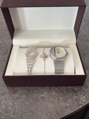 Silverfärgad klocka med glittriga detaljer - Snygg silverfärgad klocka med glittriga stenar på både urtavlan och armbandet. Klockan har ett elegant och modernt utseende med metallarmband och en unik design på urtavlan. Perfekt accessoar för dig som gillar att sticka ut.