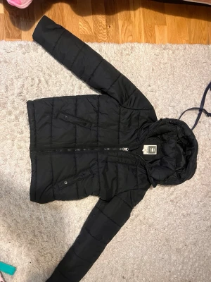 Svart pufferjacka från G-Star Raw - Säljer en svart pufferjacka från G-Star Raw med huva och dragkedja framtill. har två snedställda fickor med knappstängning och quiltad design. Perfekt för kalla dagar och riktigt snygg till streetwear-stilen. Skriv om ni har några frågor! Pris kan diskuteras!!!!