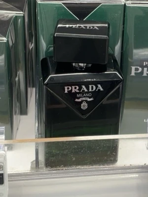 Prada Milano parfym svart/grön - Elegant parfym från Prada Milano i en stilren svart och mörkgrön glasflaska med tydlig logga på framsidan. Flaskan har en fyrkantig form och ett matchande svart lock. Perfekt för dig som gillar exklusiva dofter och snygg design.