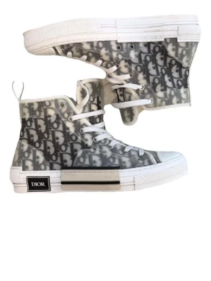 Dior B23 High Top sneakers - tjena säljer ett par snygga Dior B23 High Top Sneakers med den ikoniska Dior Oblique-designen. Perfekta för dig som vill sticka ut med exklusiva detaljer och en modern design. Skorna är lite använda och i fint skick med normalt slitage, men fungerar utmärkt och är väl omhändertagna.  De är 100 % äkta och äkthetsbevis medföljer. Säljs eftersom de inte kommer till användning.  Skicka gärna ett meddelande vid frågor eller om du vill ha fler bilder. Seriösa köpare och rimliga bud är välkomna.