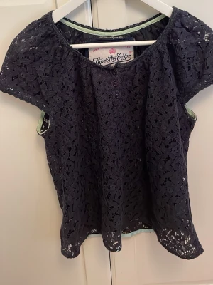 Marie blå spetsblus från Superdry - Säljer en blus från Superdry med korta ärmar och vackert spetsmönster. Blusen har rund halsringning och små knappar framtill. Den är så fin till ett par jeans eller en jeanskjol. Den är köpt second hand och är i väldigt bra skick. Jag köpte den nyligen för 200kr second hand men den var lite för stor.