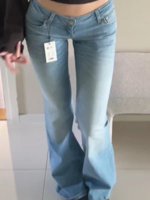 Ljusblå Blaze jeans  - Säljer ett par ljusblå blaze jeans i tall med låg midja och klassisk femficksdesign. Jeansen har en snygg tvättad look och vida ben som ger en retro känsla. Perfekta för dig som gillar en avslappnad och trendig stil.