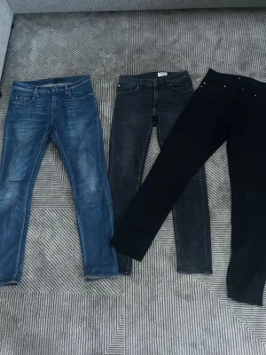 Tre par tiger of Sweden jeans  - Säljer tre par tiger of Sweden jeans i ett resell paket  i olika färger: ett par klassiska blå jeans med slitningar, ett par mörkgrå och ett par svarta. Alla har femficksmodell och smal passform. Perfekta för dig som gillar en clean och enkel stil.
