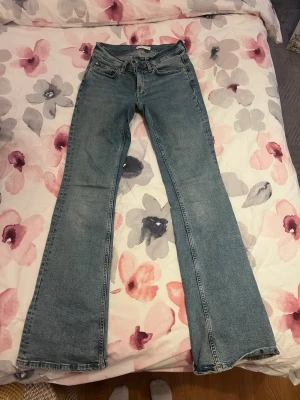 Blå bootcut jeans - Säljer ett par klassiska blå bootcut jeans i denim med fem fickor och dragkedja. Jeansen har en lätt utsvängd passform nedtill och normalhög midja. Perfekta för en avslappnad och trendig look.
