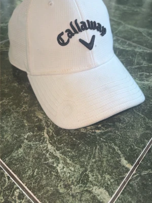 Keps - En snygg Callaway keps i vit färg med svart text. Skicket är bra, lite smutsig men går lätt bort. Hör av dig vid fler frågor eller bilder!
