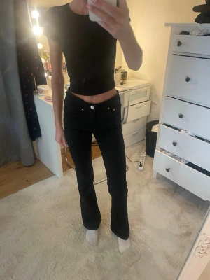 Svarta bootcut jeans från Dr. Denim - Säljer ett par svarta bootcut jeans från Gina tricot. Jeansen har klassisk femficksmodell, hög midja och smal passform upptill som går ut i ett lätt utsvängda ben. Snygga kopparfärgade nitar och knappdetalj. Perfekta till en trendig vardagslook.