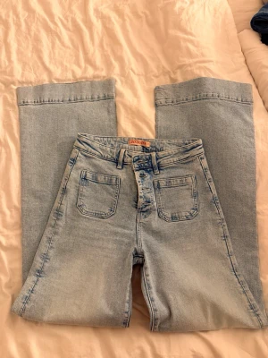Ljusblåa raka jeans från Gina Jeans - Säljer ett par ljusblåa raka jeans från Gina Jeans i storlek 36. Jeansen har hög midja, klassiska fem fickor och breda ben. Tillverkade i denim med snygg tvättad look och dubbla knappar i midjan. Perfekta för en avslappnad och trendig stil.