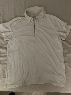 Vit polotopp från Ciszere med dragkedja - Säljer en vit polotopp från Ciszere med krage och halv dragkedja framtill. Toppen är kortärmad och har en clean, stilren look som passar perfekt till många outfits. Materialet känns mjukt och bekvämt mot huden. Står L men sitter som m