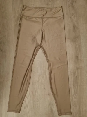 Beige leggings från H&M Move - Snygga beige leggings från H&M Move med hög midja och stretchigt material. Perfekta för träning eller chill, med en slät och mjuk yta som sitter skönt på kroppen. Stilren design utan synliga loggor framtill.