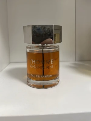 L'Homme Eau de Parfum från YSL - L'Homme Eau de Parfum från Yves Saint Laurent i en elegant glasflaska med sexkantigt silverlock. Doften har en varm bärnstensfärgad vätska och flaskan har tydlig YSL-logga på locket. Perfekt för dig som gillar exklusiva parfymer.