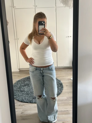 Vit v-ringad topp med kort ärm - Säljer en enkel och snygg vit topp med v-ringning och korta ärmar. Modellen är figurnära och passar perfekt till jeans eller kjol. Tillverkad i mjukt bomullsmaterial som känns skönt mot huden. En klassisk bas som funkar till allt!