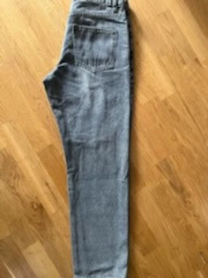 Nya Gråa raka jeans med hög midja - Säljer ett par gråa jeans med rak passform och hög midja. Jeansen har klassiska fickor både fram och bak samt resår i midjan för extra komfort. Perfekta för en avslappnad och trendig look. Aldrig använda