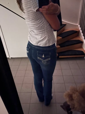Mörkblå raka jeans med mönstrade fickor - Säljer ett par mörkblå jeans med bootcut och snygga detaljer på bakfickorna. Ganska normala i midjan och passar till det mesta. tror att dessa är använda väldigt få gånger.