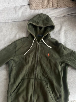 Ralph lauren zip hoodie grön - En snygg Ralph lauren zip hoodie i storlek M i färgen grön. Den är använd ett par gånger och är lite urtvättad där på de billigare priset. Kan gå ner i pris i en snabb och smidig affär! Köparen står för frakten😁