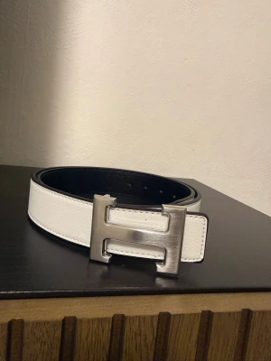 Vitt bälte  - Snyggt vitt bälte .Bältet har svarta kanter och insida, vilket ger en schysst kontrast. Perfekt accessoar för att lyfta din outfit.