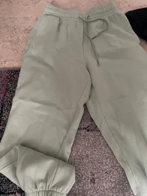 Ljusa gröna mjukisbyxor H&M - Snygga ljusgröna mjukisbyxor från H&M med resår i midjan och dragsko. Byxorna har muddar vid bensluten och är gjorda i mjukt, bekvämt material. Perfekta för chill dagar eller när du vill vara extra comfy.