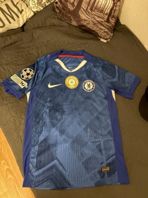 Chelsea matchtröja Palmer #10 Nike - Säljer en blå Chelsea matchtröja från Nike med Palmer och nummer 10 på ryggen. Tröjan har Champions League-märke på ärmen, FIFA Club World Cup-märke på bröstet och Chelsea FC-logga. Tillverkad i lätt funktionsmaterial, perfekt för fotboll eller träning. Det är drifit adv vilket är player version med andra ord bästa kvalitén. Längd 71 cm bredd 48 cm. Kan gå ner vid snabb affär.