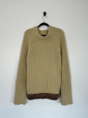 D&G Dolce & Gabbana Vintage Chunky Rib Knit Wool Blend Sweater Beige L Made in Italy - D&G Dolce & Gabbana Vintage Chunky Rib Knit Wool Blend Sweater Beige L Made in Italy Detta är en tidig D&G-linje tillverkad i Italien. Designen och hologrametiketten tyder på en kollektion i början av 2000-talet. Storlek: L Kön: Dam/Unisex Färg: Beige / sand & brun Passform: Regular fit Krage: Rund hals / Boat Neck Material: 50 % akryl & 50 % ull (virgin wool) Skick: Denna Sweater är i ett väldigt fint skick utan defekter  Nypris cirka: 5 000 kr