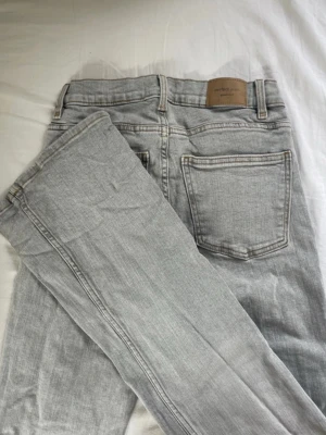 Ljusgrå bootcut jeans  - Säljer ett par ljusgrå jeans från Gina tricot  med bootcut passform och klassisk femficksdesign. Jeansen har silverfärgad knapp och dragkedja samt kontrastsömmar. Materialet är mjukt denim i bomull. Perfekta för en avslappnad och trendig look.