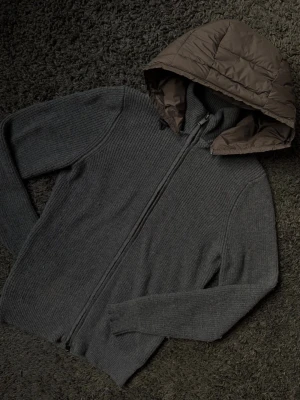 Massimo Dutti Cardigan  - Mörkgrå ribbstickad cardigan från Massimo Dutti.  Med dragkedja framtill och en avtagbar brun vadderad huva. Lite nopprig
