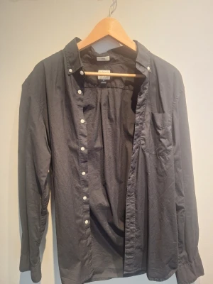 Svart/Mörkgrå skjorta från J.Crew - Snygg svart/mörkgrå skjorta från J.Crew i slim fit med stretch. Skjortan har klassisk krage, vita knappar framtill och en bröstficka. Perfekt för dig som gillar stilrena och enkla plagg.