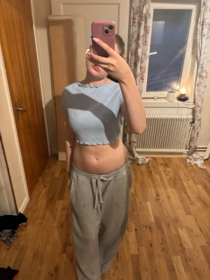 Ljusblå croppad ribbad topp - Säljer en ljusblå croppad topp med ribbad struktur och korta ärmar. Toppen har vågig kant nertill och knytning i ryggen som ger en öppen rygg-look. Perfekt för dig som gillar trendiga detaljer och en avslappnad stil.