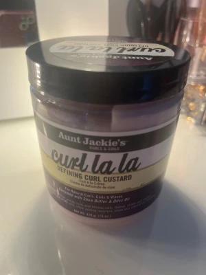 Aunt Jackie's Curl La La Curl Custard - Aunt Jackie's Curl La La Defining Curl Custard är en curl cream för lockigt hår. Innehåller sheasmör och olivolja, fri från sulfater, parabener, mineralolja och petroleum. Perfekt för att definiera lockar, coils och vågor. Är endast använd 2-5 ggr!