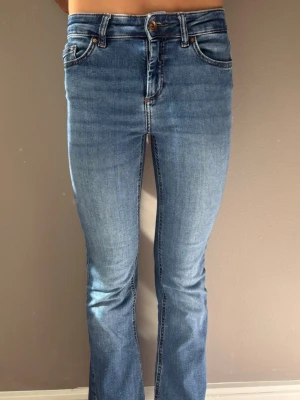 Mörkblåa raka jeans med stretch - Säljer ett par mörkblå jeans med rak passform och normal midja. Jeansen har klassiska fem fickor, bälteshällor och stängs med knapp och dragkedja. Materialet är stretchigt denim som sitter snyggt och bekvämt. Uppsydda ca 1 cm