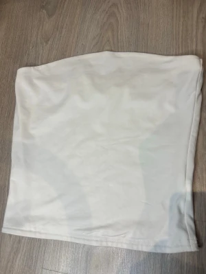 Vit axelbandslös tubtopp  - Säljer en enkel och stilren vit tubtopp i storlek M. Perfekt att matcha med jeans eller kjol för en clean look. Oanvänd