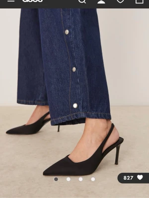 Svarta slingback pumps - Stilrena svarta pumps med spetsig tå och smal klack. Skorna har öppen häl med en elegant slingback-rem och är tillverkade i ett matt material som ger en modern look. 