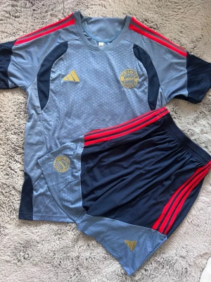 Fc Bayern München träningsett 26/27 - Ett Bayern München träningsett med T-shirt + shorts med fickor! Storlek L