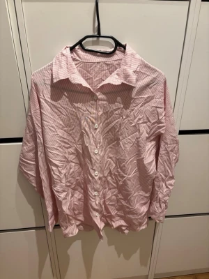 Rödvit randig skjorta med knappar - Säljer en oversized skjorta med tunna röda och vita ränder. Skjortan har klassisk krage, långa ärmar och knäppning framtill med vita knappar. Perfekt för en chill och avslappnad stil.