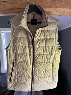 Beige dunväst från Boss - Säljer nu min stilrena väst från boss. Beige färg. Nyskick! Aldrig använd. Funkar perfekt nu mot hösten. Nypris 2500kr, mitt pris 999kr. Skriv vid intresse (inga skambud) säljes ändast till rätt pris🙌🏼mvh Edvin