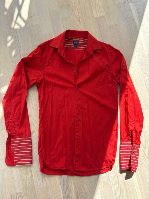 Röd skjorta från Kenzo Homme - Snygg röd skjorta från Kenzo Homme med randiga detaljer på insidan av kragen och manschetterna.