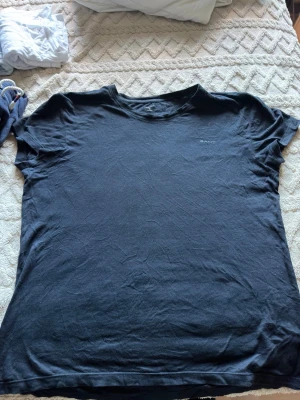 Svart t-shirt från GANT - En klassisk svart t-shirt från GANT med diskret logga på bröstet. T-shirten har rund halsringning och korta ärmar. Perfekt basplagg till garderoben och tillverkad i mjuk bomull för skön känsla.