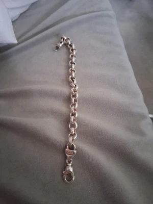 Tungt silver kedjearmband äkta silver  - Säljer ett stilrent armband i silverfärg med grova, rundade länkar och karbinhake. Armbandet har en chunky känsla och passar perfekt för dig som gillar statement-smycken. Materialet ser ut att vara metall och designen är klassisk och tidlös. Den passqr barn som är 11 år och till tjejer