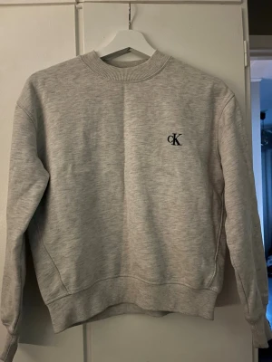 Grå sweatshirt från Calvin Klein Jeans - Säljer en  grå sweatshirt från Calvin Klein Jeans med CK-logga på bröstet. Storlek S. Använd men fint skit!