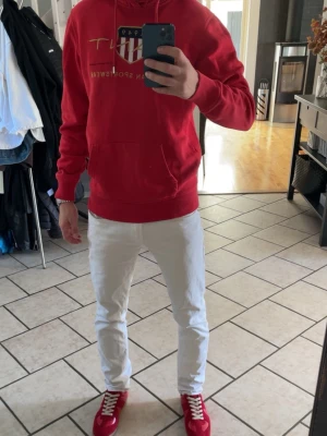 Röd hoodie från Gant med tryck - Snygg röd hoodie från Gant med stort tryck och logga på bröstet. Klassisk känguruficka framtill och justerbar huva med dragsko. Tillverkad i mjukt material som känns skönt mot huden. Perfekt för en avslappnad och sportig stil.