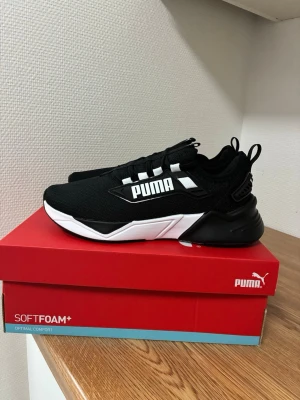 Puma Retaliate 3 sneakers svart/vit – strl 38 – oanvända med kartong - Snygga svarta sneakers från Puma med vit sula och tydlig logga på sidan. Skorna har en sportig design med mesh-överdel, svarta snören och detaljer i vitt. Perfekta för dig som gillar streetwear och vill ha bekväma skor med SoftFoam+ innersula.  