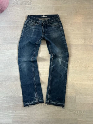 Mörkblå raka jeans från acne jeans 28/32 tjejmodell - Säljer ett par mörkblå jeans från acne med raka ben och slitna detaljer vid benslut. Jeansen har klassisk femficksmodell, kontrastsömmar och är tillverkade i denim. Perfekta för en avslappnad och trendig look.