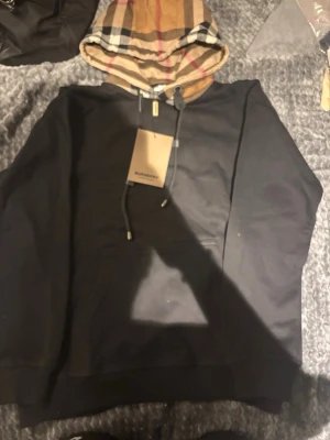 Svart hoodie med Burberry-mönstrad huva - svart hoodie med klassisk Burberry-rutig huva och dragsko. 