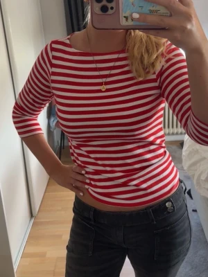 Rödvit randig topp från H&M - Säljer en rödvit randig topp från H&M L.O.G.G. i storlek XS. Toppen har trekvartsärm och är gjord i mjuk bomull. Perfekt för dig som gillar klassiska ränder och en slim passform.