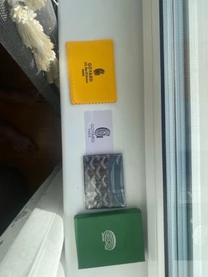 Plånbok - Säljer en svart korthållare  med klassiskt vitt och grått mönster. Kommer med original grön ask, gul putsduk och äkthetskort. Perfekt för dig som vill ha en stilren och exklusiv accessoar till dina kort.