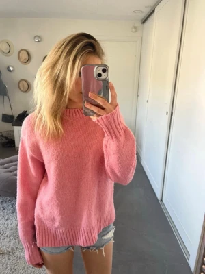 Oversized rosa stickad tröja - Mysig oversized stickad tröja i en härlig rosa färg. Tröjan har rund halsringning, långa ärmar och ribbade muddar vid ärmslut och nederkant. Perfekt för att addera färg till din outfit och superbekväm att bära.