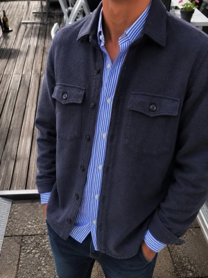 Selected Homme Navy Overshirt – Strl S - Snygg och stilren navy/mörkblå overshirt från Selected Homme. Modellen har en lite grövre och mjuk/fluffig materialkänsla, klassisk skjortkrage, mörka knappar och två stora bröstfickor med knapp.  Perfekt som ett extra lager över en skjorta, T-shirt eller tröja och passar både till jeans och chinos. En tidlös modell som fungerar bra till både vardag och en mer uppklädd outfit.  Märke: Selected Homme Storlek: S (EU) Färg: Navy / mörkblå Modell: Overshirt LS W