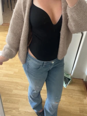 Ljusblå raka jeans med slitningar - Säljer ett par ljusblå jeans med raka ben och diskreta slitningar på knäna. Jeansen har klassisk femficksmodell och normal midja. Perfekta för en avslappnad och trendig look.