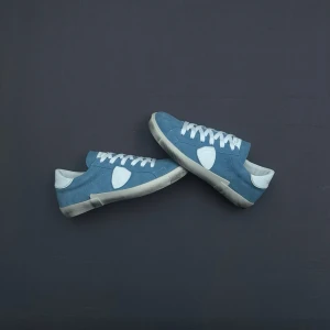 Blå Philippe model sneakers med vita detaljer - Snygga Philippe models i ljusblå mocka med vita detaljer och vita skosnören. Skorna har en låg profil och vit sula som ger en clean look. Perfekta för dig som gillar stilrena och klassiska sneakers med en twist.